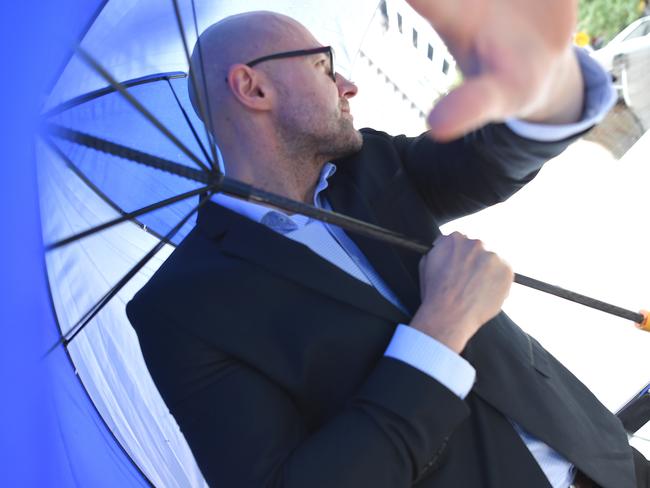 Dragi Stojanovski, Snezana’s husband, hides behind an umbrella as he leaves court. Picture: Nicole Garmston