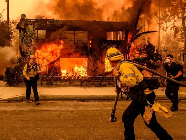 TOPSHOT - Firefighters work the scene as an apartment building burns during the Eaton fire in the Altadena area of Los Angeles county, California on January 8, 2025. At least five people are now known to have died in wildfires raging around Los Angeles, with more deaths feared, law enforcement said January 8, as terrifying blazes leveled whole streets, torching cars and houses in minutes. More than 1,000 buildings have burned in multiple wildfires that have erupted around America's second biggest city, forcing tens of thousands of people from their homes. (Photo by JOSH EDELSON / AFP)