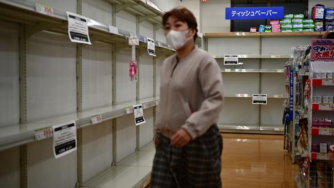 A woman walks past shelves where toilet paper was stocked and now sold out, at a shop in Tokyo. Picture: AFP