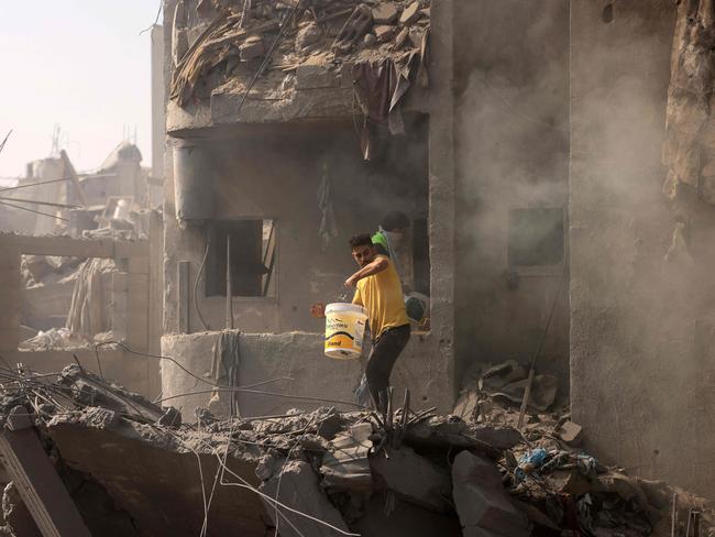 Men pour water over the smouldering rubble of a building destroyed in an Israeli strike on the Bureij refugee camp in the central Gaza Strip. Picture: AFP