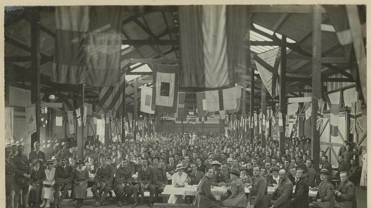 Armistice Day 1918. One thousand returned soldiers being entertained to dinner in a large warehouse at Outer Harbor, South Australia; the area is hung with flags, a small number of women sit in the foreground. Must credit: Picture: State Library SA. PRG 280/1/26/190.