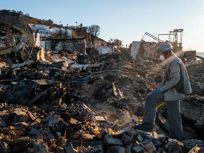 MALIBU, CALIFORNIA - JANUARY 13: Patrick O'Neal sifts through his home after it was destroyed by the Palisades wildfire on January 13, 2025 in Malibu, California. "I'm trying to figure out where I am in the house... I think i'm standing in my dad's bathroom. To be honest, I don't even know what I'm looking for I guess I'm just trying to make sense of it. There's nothing left, just ash and bricks-there's nothing," said O'Neal. Multiple wildfires fueled by intense Santa Ana Winds are burning across Los Angeles County. Reportedly at least 25 people have died with over 180,000 people under evacuation orders. Over 12,000 structures have been destroyed or damaged, while more than 35,000 acres have burned.   Brandon Bell/Getty Images/AFP (Photo by Brandon Bell / GETTY IMAGES NORTH AMERICA / Getty Images via AFP)