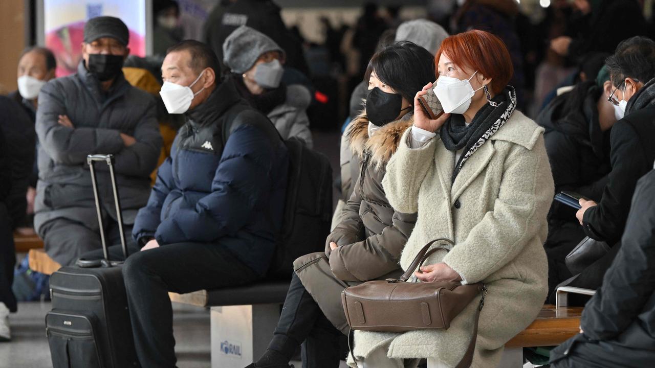 People wearing face masks sit on benches at a railway station in Seoul on January 30. Picture: AFP