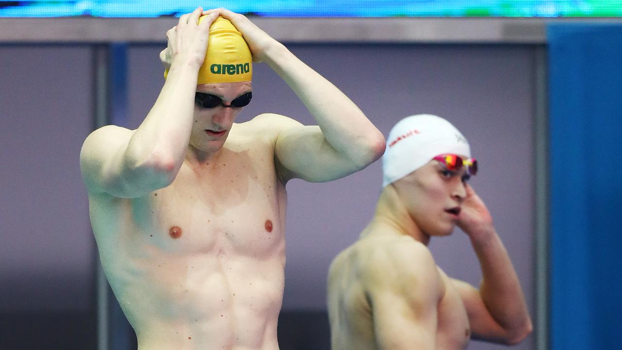 Mack Horton prepares to compete in the men's 800m Freestyle heats as Sun Yang exits the pool deck.