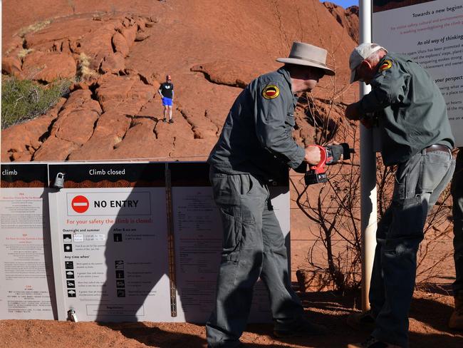 Rangers take down signs at the base of Uluru. Picture: AFP