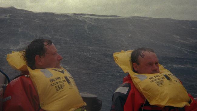 Crewmen on the yacht Stand Aside as a wall of water approaches.