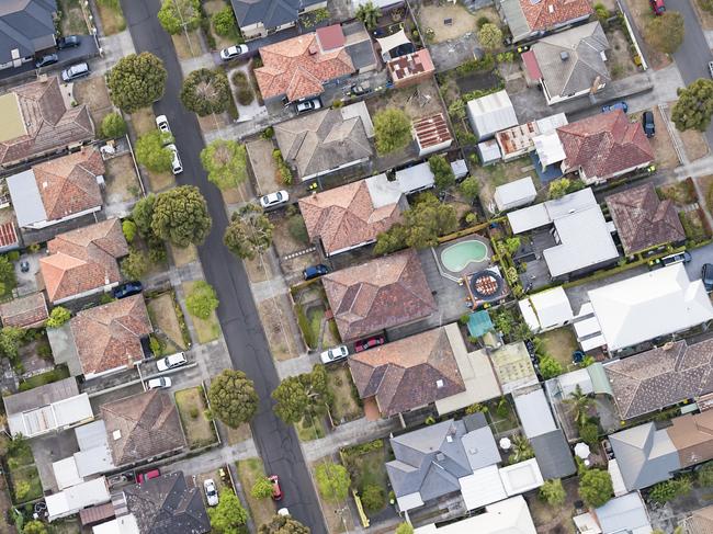 A view of suburban detached houses, gardens, streets and cars from directly above.