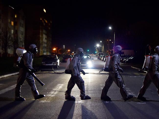 Belarus' servicemen wearing protective gear cross a road after disinfecting a hospital in the town of Zaslauye, outside Minsk. Picture: Sergei Gapon