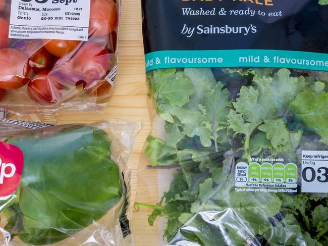 Poole, UK - September 1, 2016: Plastic wrapped salad vegetables including cherry tomatos, mixed baby kale and bell peppers on a wooden kitchen surface. Plastic wrapping includes the Sainsbury's logo. Prepackaged food. Text on the packaging includes use by dates of 05 Sept and 03 Sept and 99p + nutrional information charts. The peppers are priced at 99p.