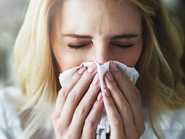 Shot of a frustrated businesswoman using a tissue to sneeze in while being seated in the office