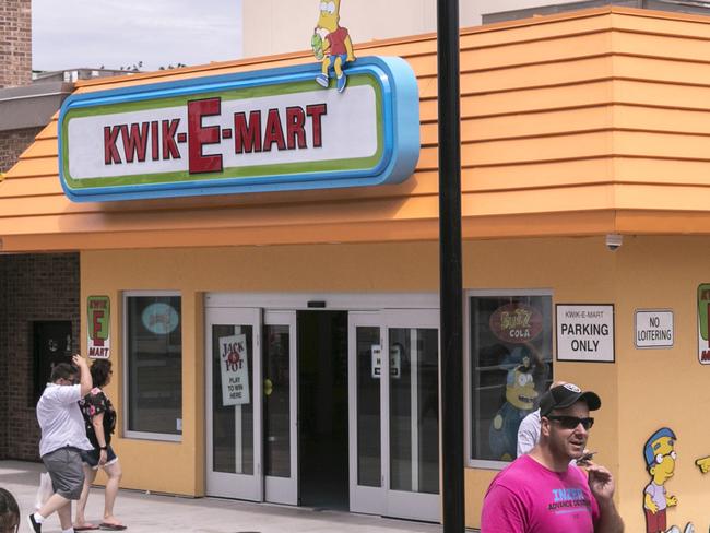 People walk past the Simpson's inspired Kwik-E-Mart at Broadway at the Beach in Myrtle Beach, S.C., on Aug. 17, 2018.  The mart will sell Buzz Cola, heat-lamp hot dogs and Lard Lad Donuts, as well as Squishee flavored drinks from the show.  (Jason Lee/The Sun News via AP)