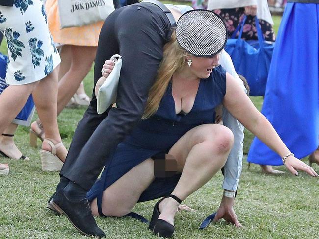 The lady in the blue dress and dainty fascinator attempts a fireman’s lift of a male friend on the course at Flemington. Picture: Getty.