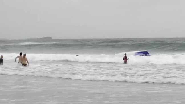 Surf boat rolls in big swell in front of Anzac Day crowd