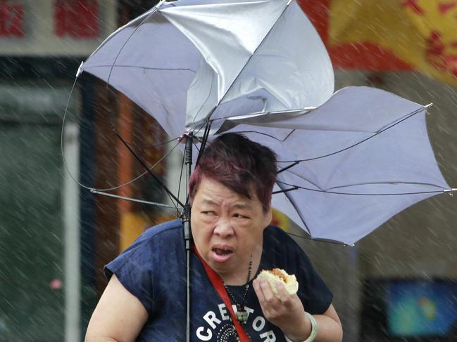A woman eats and struggles with her umbrella against powerful gusts of wind generated by typhoon Megi across the the island in Taipei, Taiwan, Tuesday, Sept. 27, 2016. Schools and offices have been closed on Taiwan and people in dangerous areas have been evacuated as a large typhoon with 162 kilometers- (100 miles-) per-hour winds approaches the island. (AP Photo/Chiang Ying-ying)