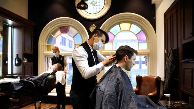 Barber Alberto Suryajaya and Amy Lewns don face masks while attending to customers at Truefitt and Hill in Sydney’s Queen Victoria Building. Picture: Jane Dempster