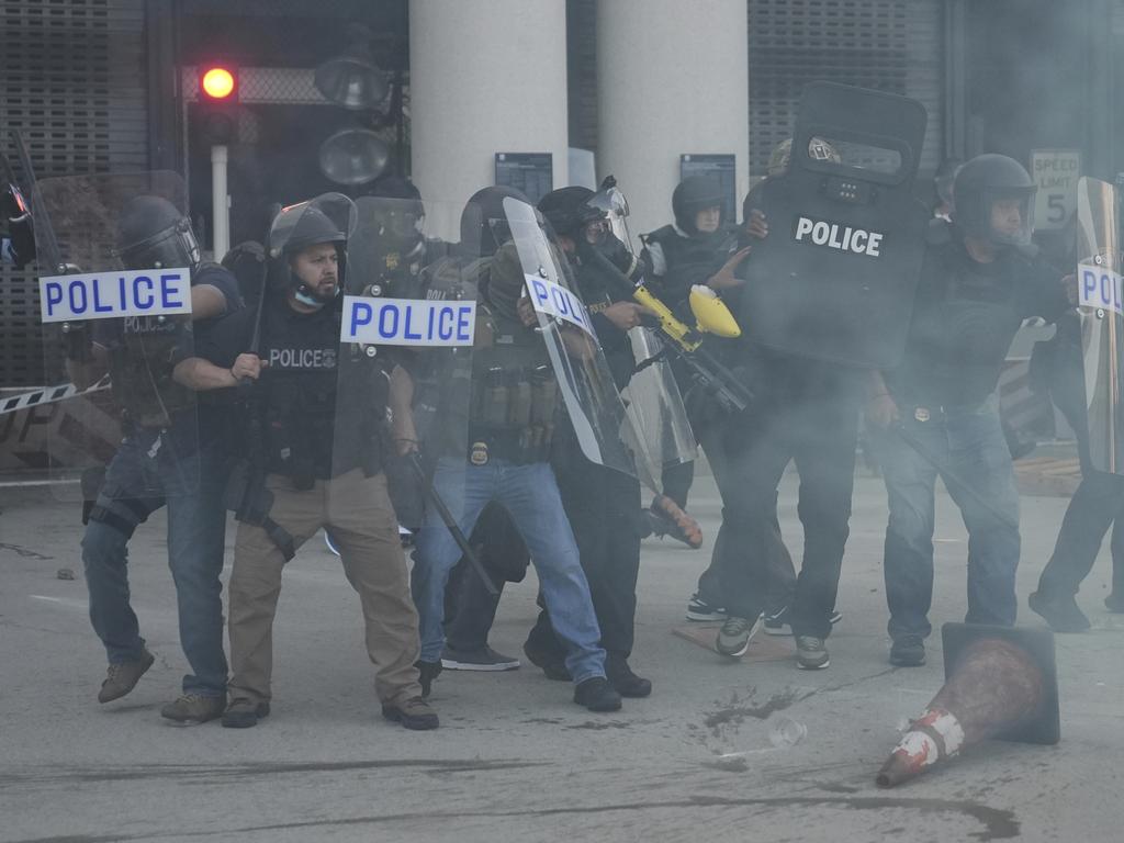 Law enforcement officers gather as tear gas fills the air during a protest after federal immigration authorities conducted an operation. Picture: AP