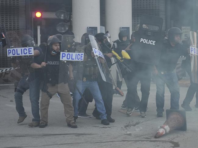Law enforcement officers gather as tear gas fills the air during a protest after federal immigration authorities conducted an operation. Picture: AP
