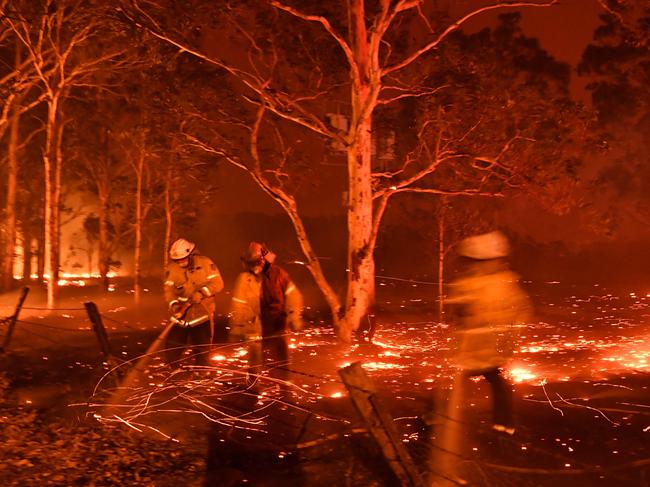 Firefighters hose down the area as they battle against bushfires around the town of Nowra in the Australian state of New South Wales on December 31, 2019. - Thousands of holidaymakers and locals were forced to flee to beaches in fire-ravaged southeast Australia on December 31, as blazes ripped through popular tourist areas leaving no escape by land. Picture: Saeed Khan/AFP