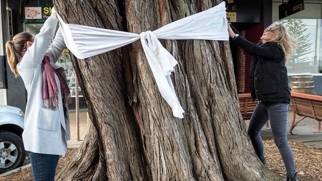 Women tie a white ribbon to a tree in Cowes in tribute to murder victim Samantha Fraser. Picture: Jake Nowakowski