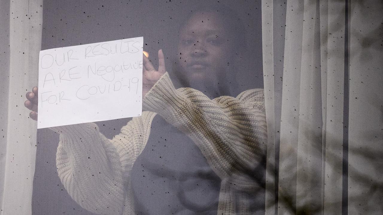 A woman holds up a sign reading ‘Our results are negative for COVID-19’ from her room at the Radisson Blu hotel near Heathrow Airport. Picture: Leon Neal/Getty