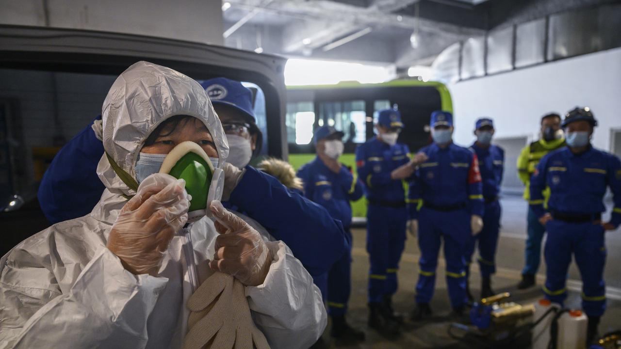 A female Chinese volunteer from Blue Sky Rescue puts on a mask as she wears a protective suit before fumigating and disinfecting an area of a local bus station last week. Picture: Kevin Frayer/Getty Images.