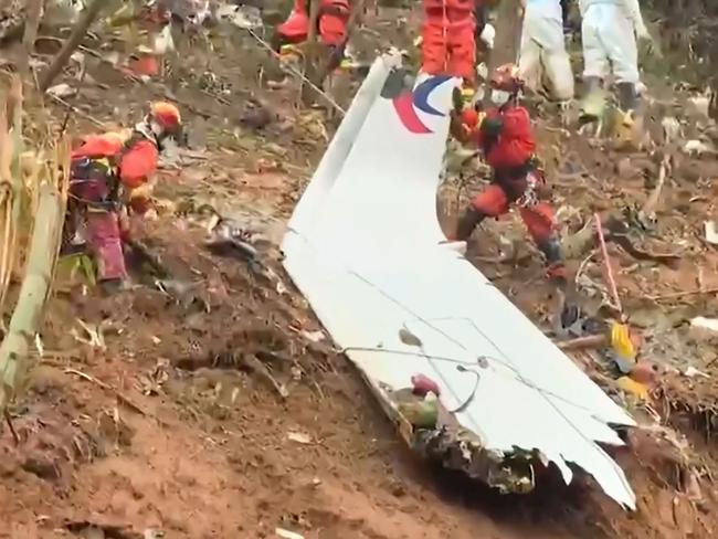 Rescue teams with a piece of the fuselage as they continued their search at the site. Picture: AFP