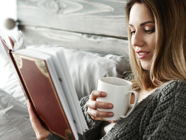 Woman drinking coffee and reading book on bedWellbeing from istock for Gold Coast Eye