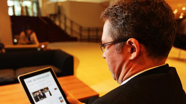 A reader looks uses his Apple iPad to download an electronic version of The Australian newspaper.