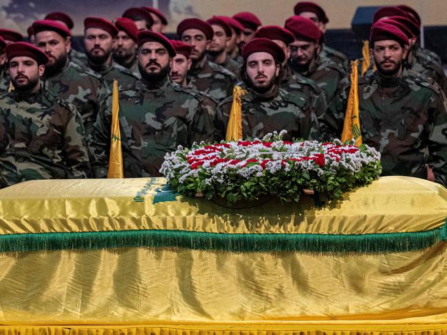 Hezbollah fighters stand guard next to the flag-draped coffin of slain top commander Fuad Shukr during his funeral ceremony in Beirut's southern suburbs. Picture: AFP