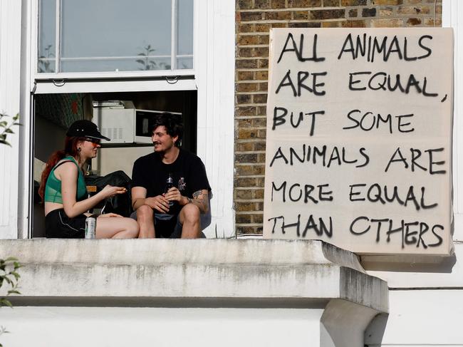 Demonstrators sit on a windowsill with a placards as they protest near the home of 10 Downing Street special adviser Dominic Cummings. Picture: AFP