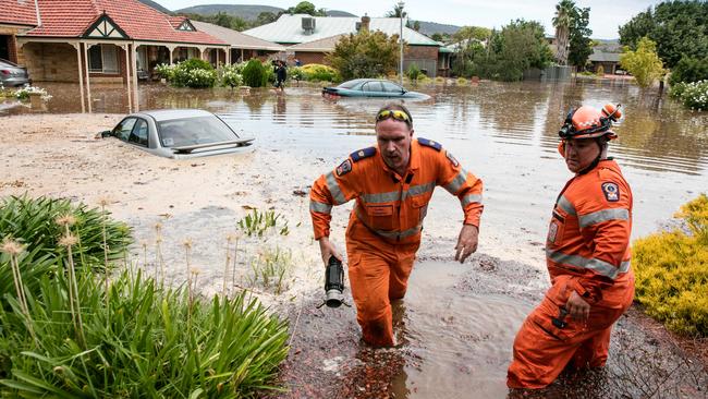 Two SES workers help residents after being flooded apparently due to a water main burst in Willow Drive, Paradise. Picture: Russell Millard