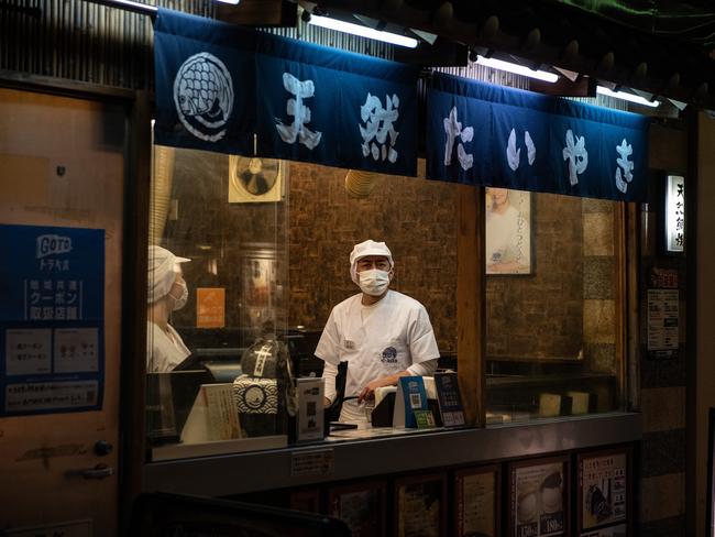 A chef wearing a face mask looks out from a restaurant window in Tokyo, Japan.