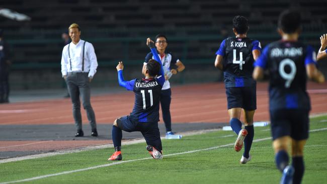 Cambodia's national football team manager Keisuke Honda (L) watches while Cambodia's forward Chan Vathanaka (2nd-L) celebrates