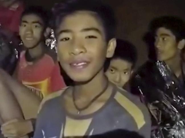 FILE - In this July 3, 2018, file image taken from video provided by the Royal Thai Navy Facebook Page, the boys smile as Thai Navy SEAL medic help injured children inside a cave in Mae Sai, northern Thailand. The group was discovered July 2 after 10 days totally cut off from the outside world, and while they are for the most physically healthy, experts say the ordeal has likely taken a mental toll that could worsen the longer the situation lasts. (Royal Thai Navy Facebook Page via AP, File)