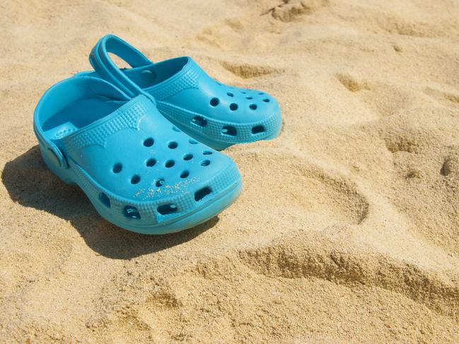 vacation by the sea: casual blue clog shoes on the sand on the beach