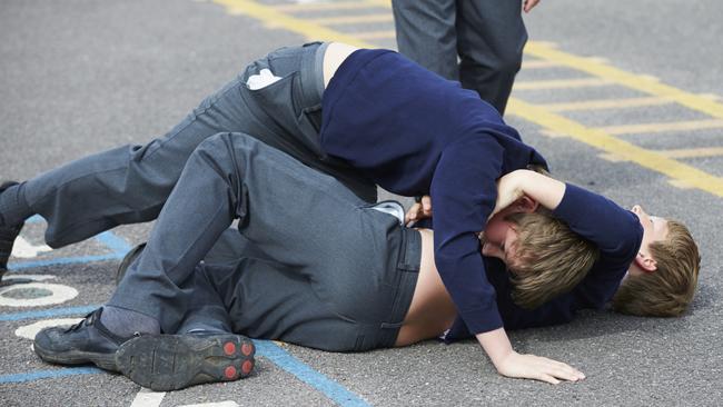 Two boys fight in the school playground during break time.