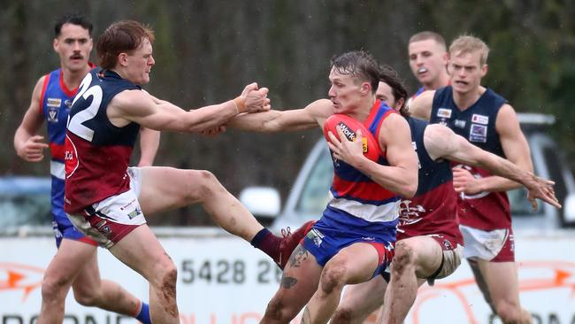 Gisborne star Brad Bernacki fends off a Sandhurst opponent.