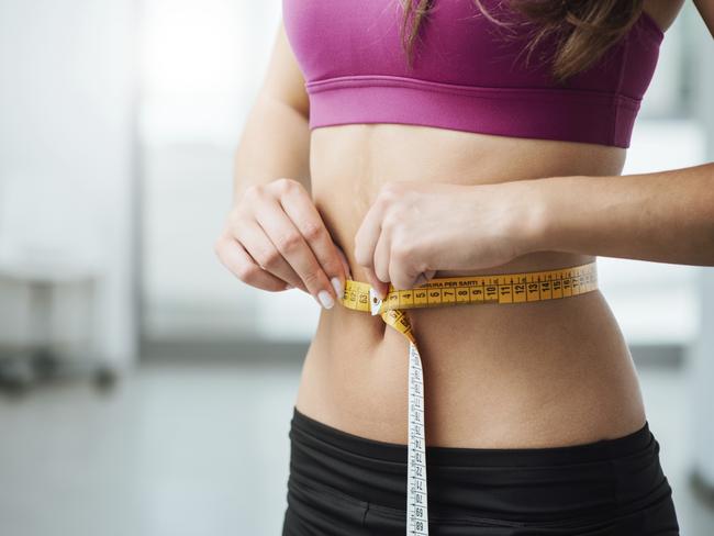 Gold Coast Suns - My Life.Slim young woman measuring her thin waist with a tape measure, close up