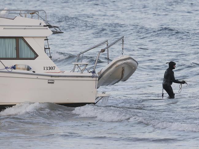 Tasmania Police member pulling a rope to attached to the boat to be towed.  Boat washed up on Kingston Beach with no one on board.  Picture: Nikki Davis-Jones