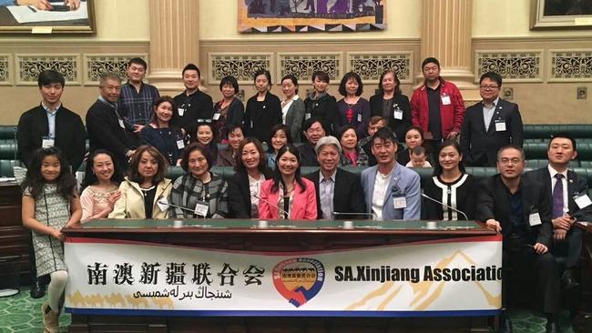 Jing Lee (centre, pink jacket) poses with the SA Xinjiang Association on the Government benches in SA Parliament after giving them a tour of the building in September 2016.