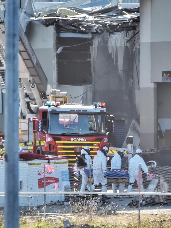 Forensic crews remove a body from the plane. Picture: Tony Gough