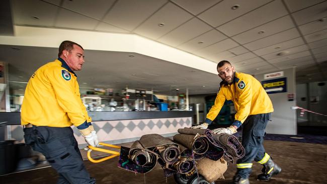 Members of the Hobbity RFS ripping up and removing saturated and ruined carpet at The Camden Sports Club in Camden. Picture: Julian Andrews