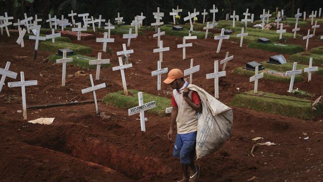 A man walks past newly dug graves for those suspected of dying from Covid-19 in Jakarta. Picture: Getty Images