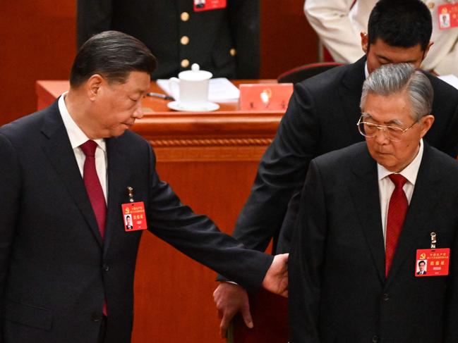 China's President Xi Jinping (L) helps former president Hu Jintao (front R) to his seat during the opening session of the 20th Chinese Communist Party's Congress at the Great Hall of the People in Beijing on October 16, 2022. (Photo by Noel CELIS / AFP)