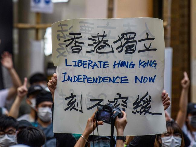 (FILES) This file photo taken on July 1, 2020 shows protesters chant slogans and hold a placard during a rally against a new national security law in Hong Kong, on the 23rd anniversary of the city's handover from Britain to China. - From remote Himalayan valleys to small tropical islands and tense Western capitals, an increasingly assertive China is taking on conflicts around the world like never before as the United States retreats. (Photo by Anthony WALLACE / AFP) / TO GO WITH AFP STORY CHINA-POLITICS-DIPLOMACY,FOCUS BY JING XUAN TENG