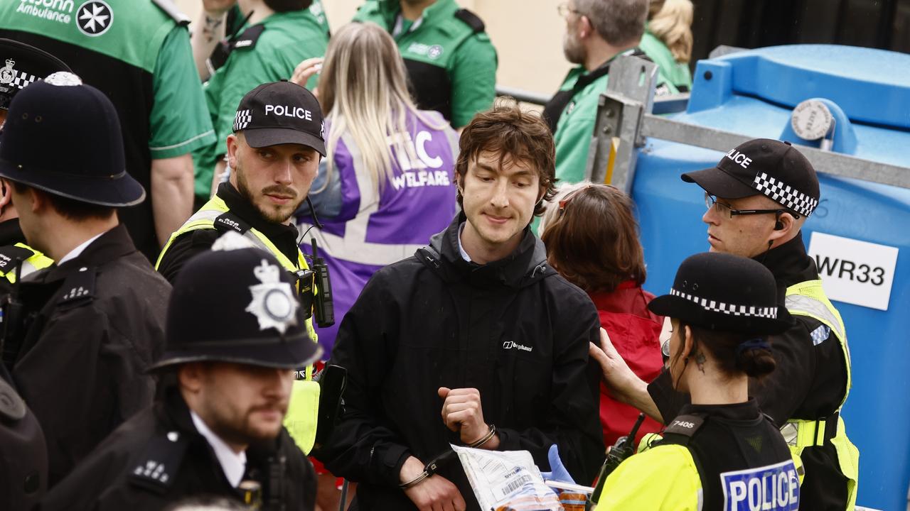 Police officers detain a member of "Just Stop Oil" movement as people gather to watch the procession. Picture: Getty Images