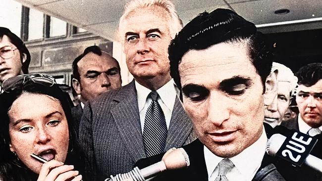 A stunned Gough Whitlam stands on the steps of Parliament House listening to an official read a statement to the press. Picture: Maurie Wilmott