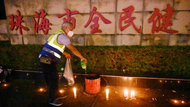 A worker douses candles left outside the Zhuhai Sports Centre, a day after a car rammed through the site killing dozens in Zhuhai, in south China's Guangdong province on November 12, 2024. (Photo by Michael Zhang / AFP)