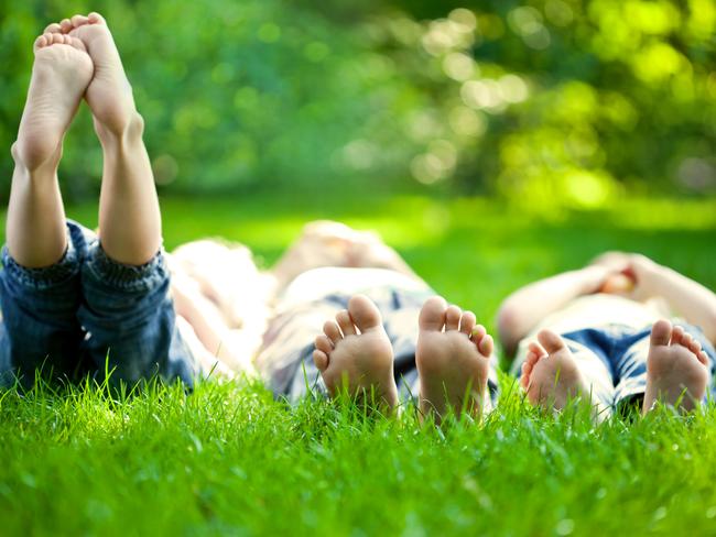 Group of happy children lying on green grass outdoors in spring park.