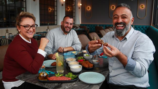 Abbie Bayad and Roger Al Hachem enjoy a meal with restaurant owner, Osama Haddad, at their new location in Bass Hill. Picture: Justin Lloyd.